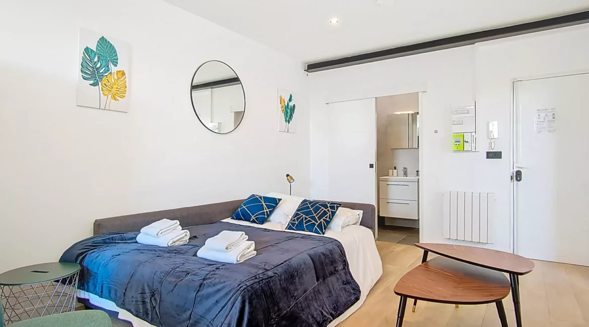 canape lit location appartement court sejour argenteuil Chambre moderne avec salle de bain et décoration colorée.