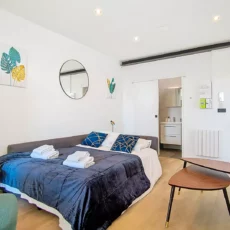 canape lit location appartement court sejour argenteuil Chambre moderne avec salle de bain et décoration colorée.