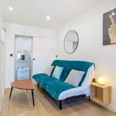 canape salle de bain apparente location appartement argenteuil Salon moderne et épuré avec canapé et miroir.