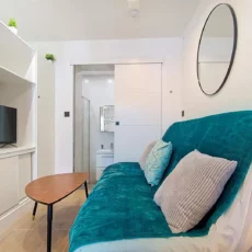 canape turquoise salle de bain location appartement argenteuil Salon moderne avec canapé turquoise et miroir rond.