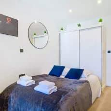 chambre avec salle de bain location appartement argenteuil Chambre moderne avec lit et miroir.