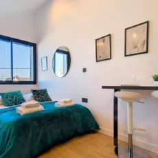 Chambre moderne avec lit double, lumières et table haute.