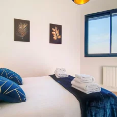 chambre ensoleillee cosy location appartement court sejour argenteuil Chambre lumineuse avec lit et coussins bleus.