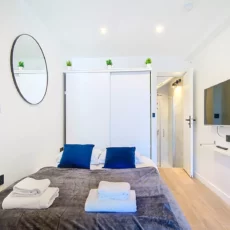 chambre lit tv location appartement argenteuil Chambre moderne avec lit, télévision et miroir.