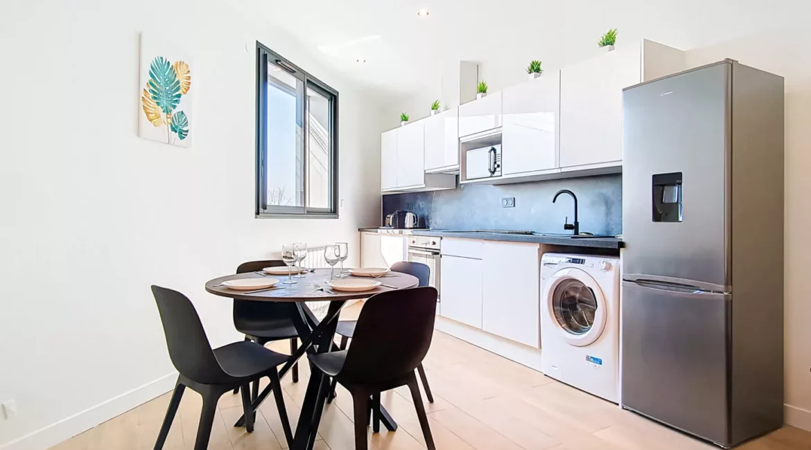 coin repas cuisine location appartement court sejour argenteuil Cuisine moderne avec réfrigérateur et table à manger.