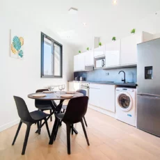 coin repas cuisine location appartement court sejour argenteuil Cuisine moderne avec réfrigérateur et table à manger.