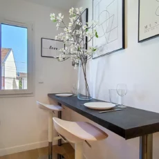 coin repas fenetre decoration location appartement argenteuil Coin repas moderne avec tabourets hauts et décoration florale.