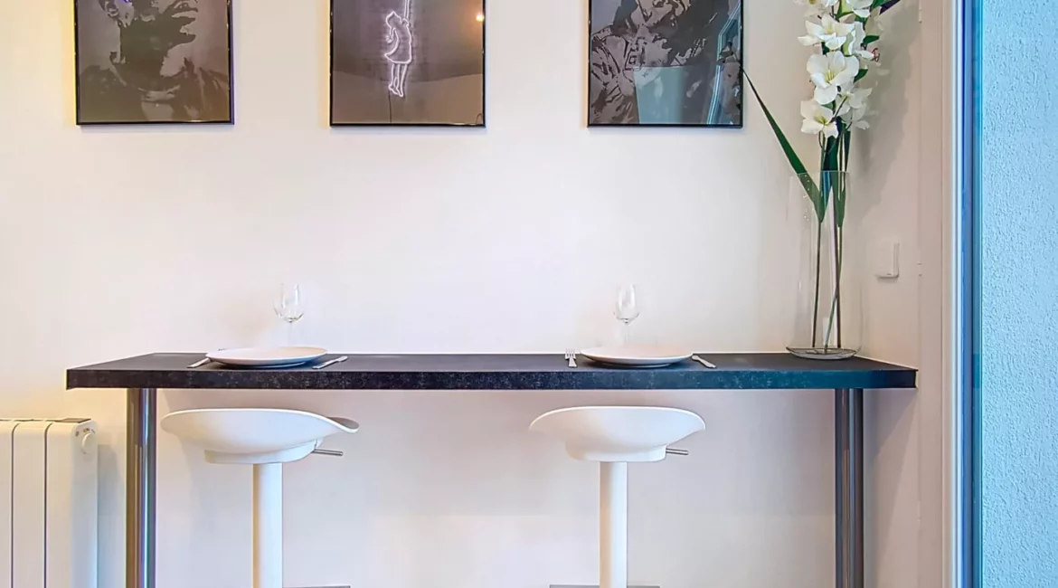 coin repas moderne location appartement argenteuil Cuisine moderne avec tabourets et tableaux muraux.