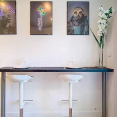 coin repas moderne location appartement argenteuil Cuisine moderne avec tabourets et tableaux muraux.