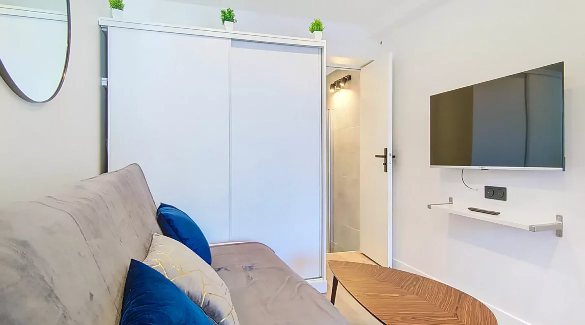 coin salon tv location appartement argenteuil Salon moderne avec canapé et télévision murale.