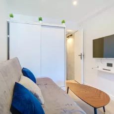 coin salon tv location appartement argenteuil Salon moderne avec canapé et télévision murale.