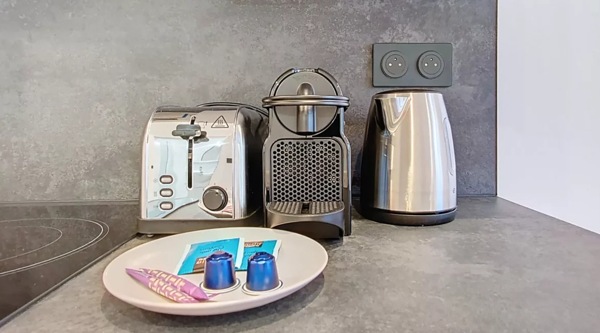 cuisine grille pain, cafetière, bouilloire et capsule location appartement argenteuil Appareils de cuisine avec dosettes de café sur comptoir.