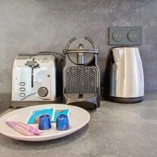 cuisine grille pain, cafetière, bouilloire et capsule location appartement argenteuil Appareils de cuisine avec dosettes de café sur comptoir.