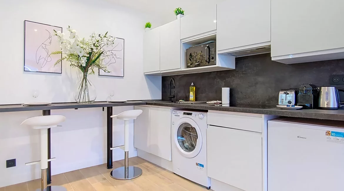 cuisine moderne avec comptoir et tabourets blancs location appartement argenteuil Cuisine moderne avec comptoir et appareils électroménagers.