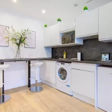 cuisine moderne avec comptoir et tabourets blancs location appartement argenteuil Cuisine moderne avec comptoir et appareils électroménagers.