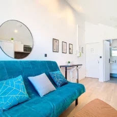 Salon moderne avec canapé turquoise et miroir rond.