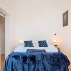 lit double avec decoration murale location appartement court sejour argenteuil Chambre moderne avec lit, décor bleu.