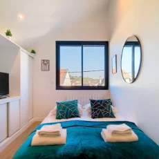 Chambre lumineuse avec lit, fenêtre et miroir rond.