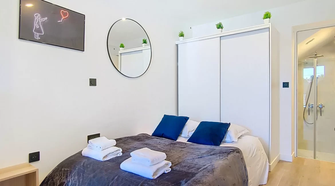 lit double rangements location appartement argenteuil Chambre moderne avec lit double et décoration minimaliste.