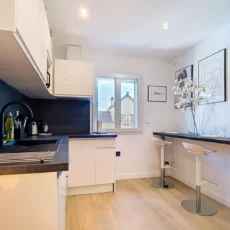 plan large cuisine salon location appartement argenteuil Cuisine moderne avec table haute et chaises blanches.