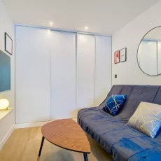 Salon moderne avec canapé bleu et télévision.