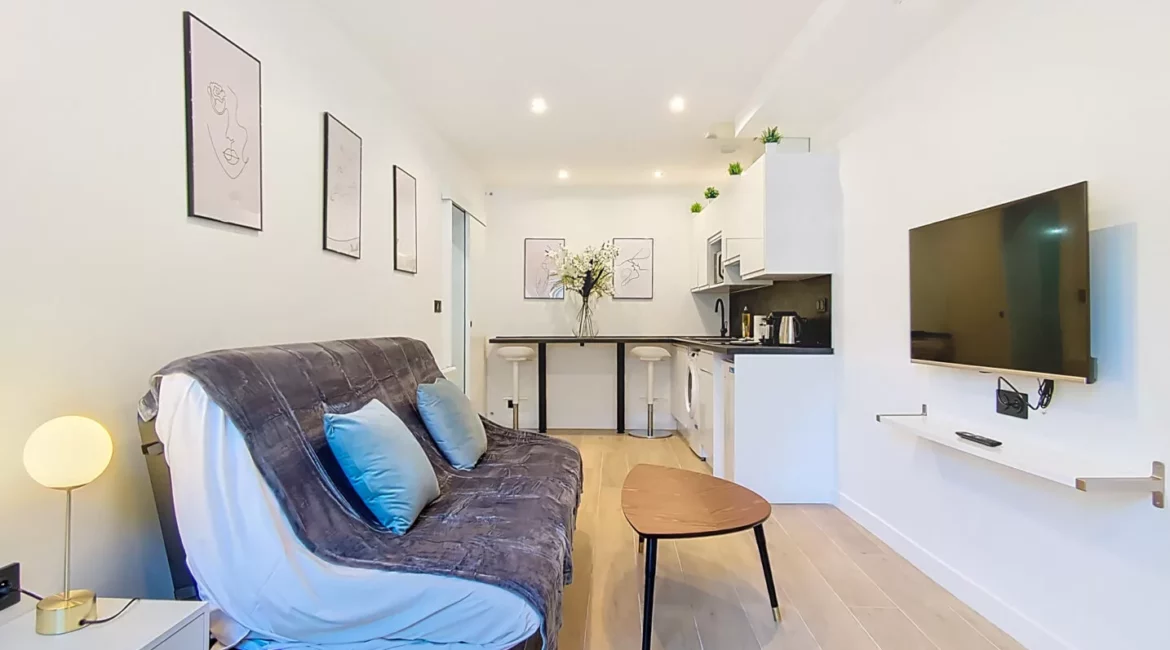 salon moderne avec canapé et coin cuisine location appartement argenteuil Salon moderne avec canapé et télévision murale.