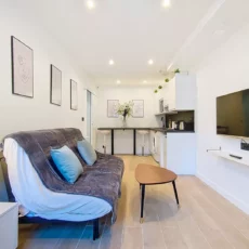salon moderne avec canapé et coin cuisine location appartement argenteuil Salon moderne avec canapé et télévision murale.