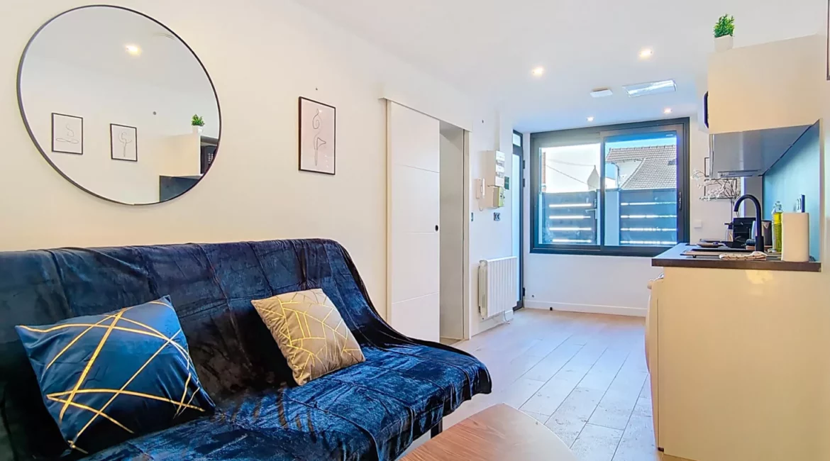 Salon moderne avec canapé et cuisine ouverte.