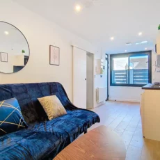 Salon moderne avec canapé et cuisine ouverte.