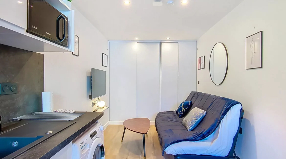 Salon moderne avec canapé et coin cuisine.