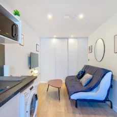 Salon moderne avec canapé et coin cuisine.