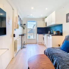 vue salon cuisine location appartement argenteuil Salon moderne avec cuisine intégrée et canapé.