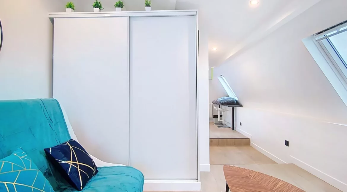 armoire appartement vie d'artiste argenteuil Salon moderne avec canapé turquoise et table basse.