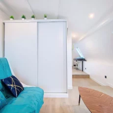 armoire appartement vie d'artiste argenteuil Salon moderne avec canapé turquoise et table basse.