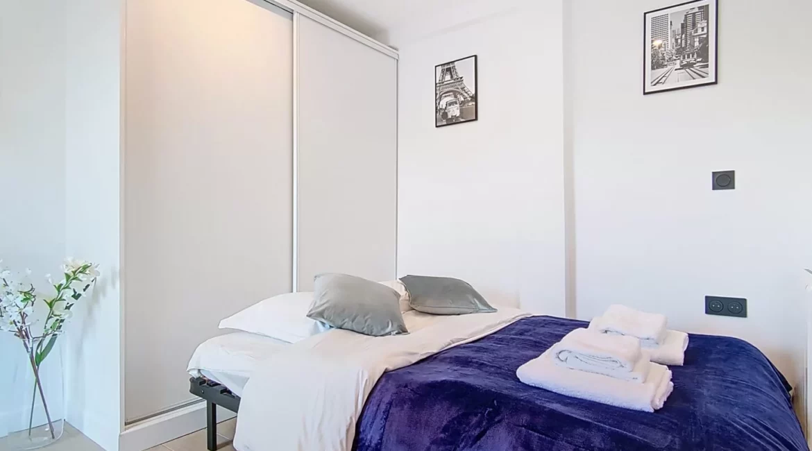 canapé lit location studio voyage argenteuil Chambre moderne avec lit et décor minimaliste.