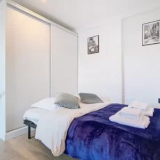 canapé lit location studio voyage argenteuil Chambre moderne avec lit et décor minimaliste.