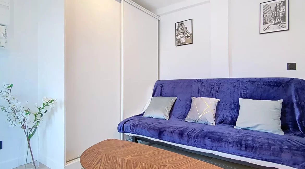 canapé location studio voyage argenteuil Salon moderne avec canapé bleu et table en bois.