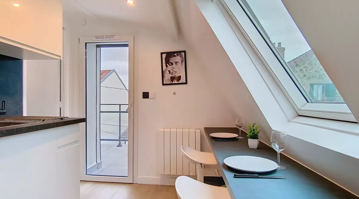 coin repas appartement vie d'artiste argenteuil Cuisine lumineuse avec table et tabourets dans grenier.