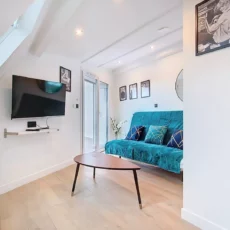 coin séjour appartement vie d'artiste argenteuil Salon moderne avec canapé bleu et télévision murale.