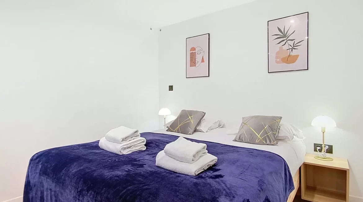 Chambre moderne avec lit double et décoration murale.