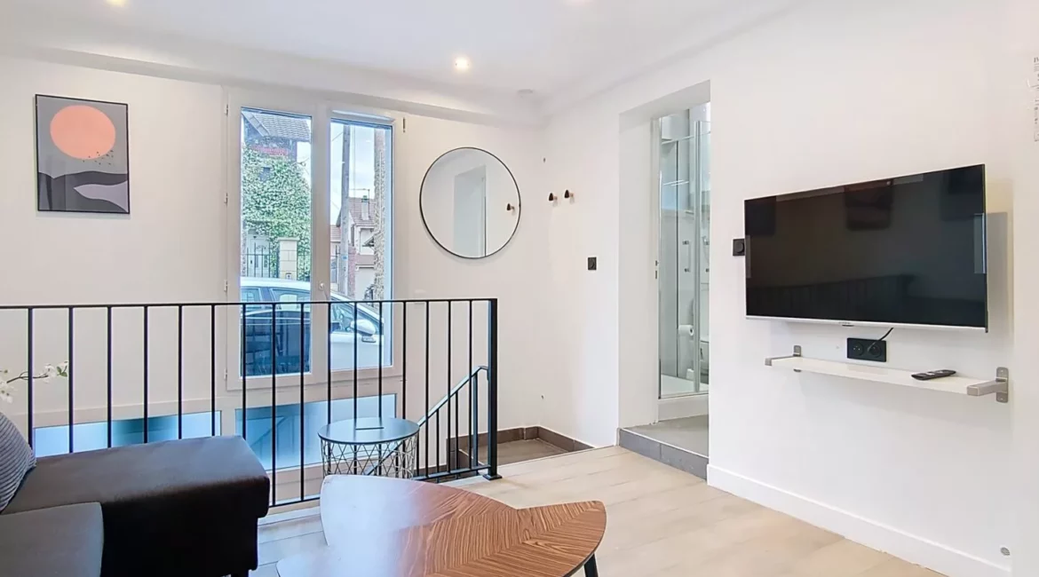 Salon moderne avec télévision murale et canapé.