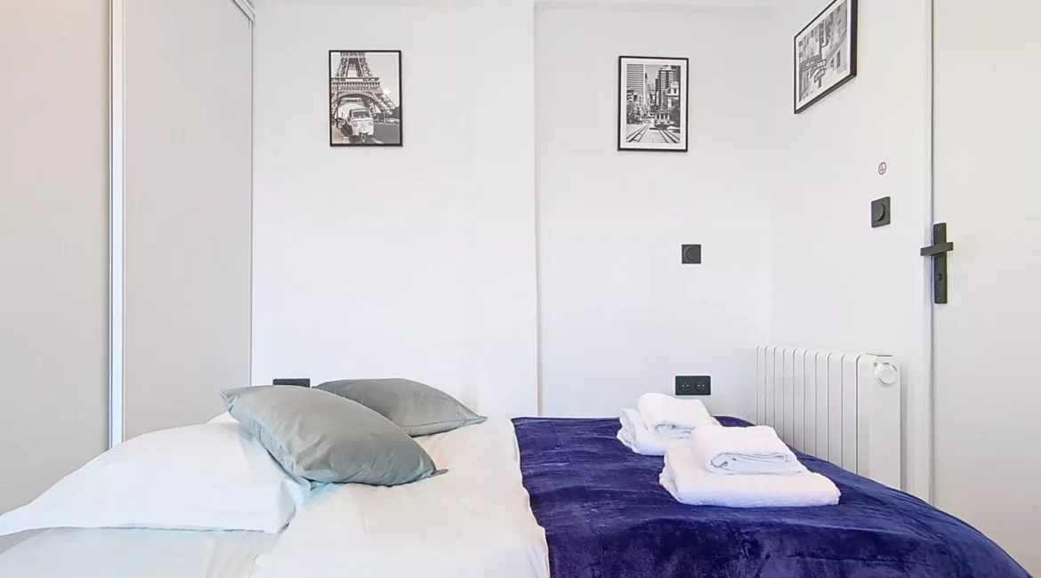 lit 2 personnes location studio voyage argenteuil Chambre moderne avec lit et décorations murales.