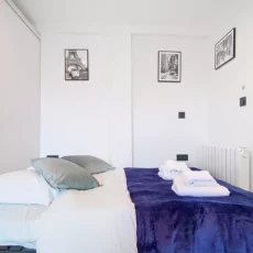 lit 2 personnes location studio voyage argenteuil Chambre moderne avec lit et décorations murales.