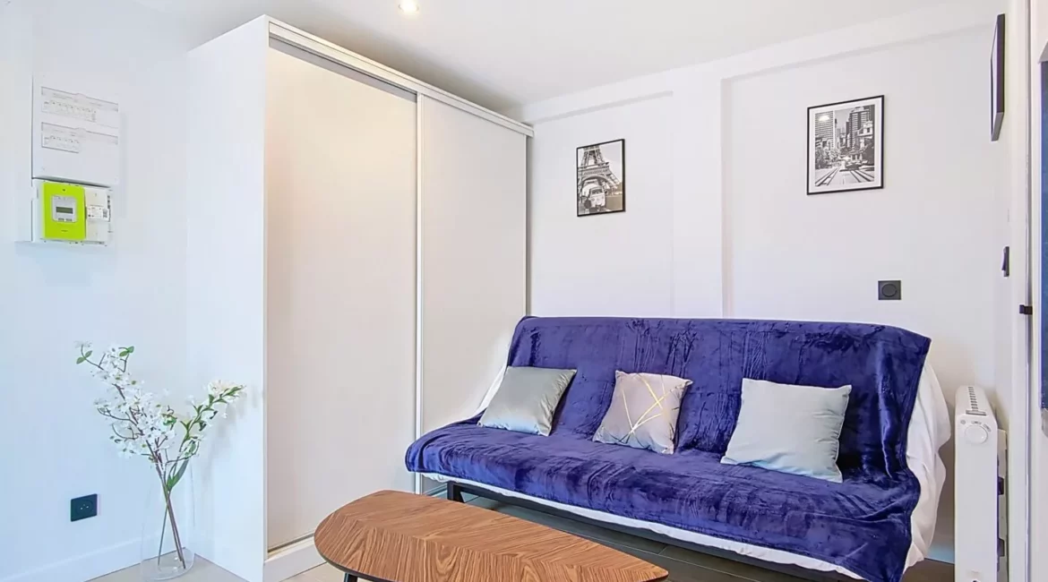 salon location studio voyage argenteuil Salon moderne avec canapé bleu et décorations murales.