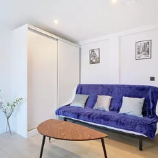 salon location studio voyage argenteuil Salon moderne avec canapé bleu et décorations murales.