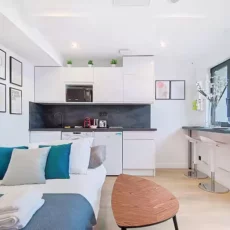 Studio moderne avec cuisine équipée et table.