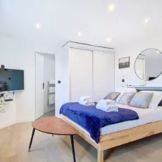 Chambre moderne avec lit double, TV et miroir.