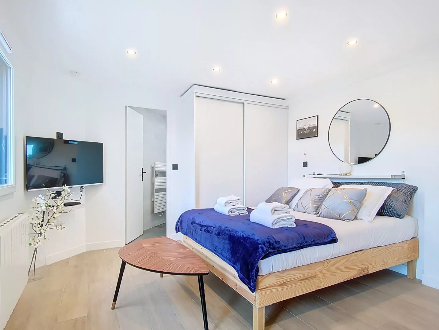 Chambre moderne avec lit double, TV et miroir.