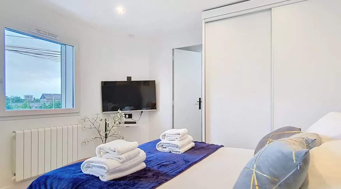 Chambre moderne avec lit et télévision murale.