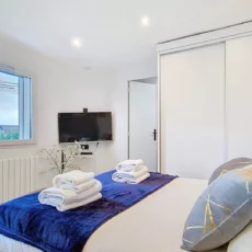 Chambre moderne avec lit et télévision murale.